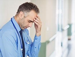 Blog_PhysicianBurnout_MedProfStressedHandHeadNursesBkgdCropped_260x200px